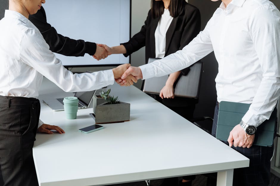 Business professionals shaking hands over a deal at a modern office table.